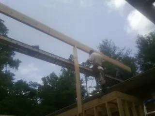 Carpenter setting a ridge beam over a new addition frame — Ice Dam Removal by Roofing Brothers in Santa
