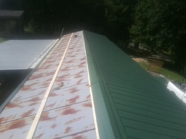 Old rusted panels beside newly installed green metal roofing — Wind Damage Roof Repair by Roofing Brothers in Santa