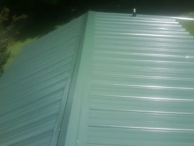 New green metal panels meeting at the ridge of a roof — Flat Roof Repair work by our crew in Santa