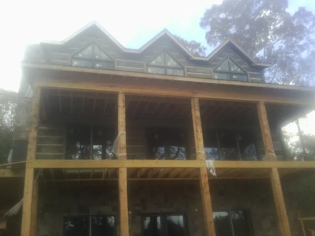 Dormers and porch framing on a large log home under construction — Roof Coating work by our crew in Santa