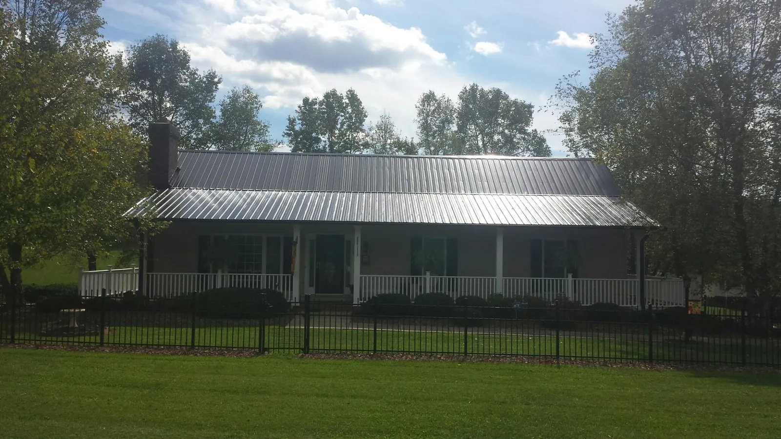 Gray metal roof on a brick ranch with a full width front porch — Gutter Guard Installation work by our crew in Santa