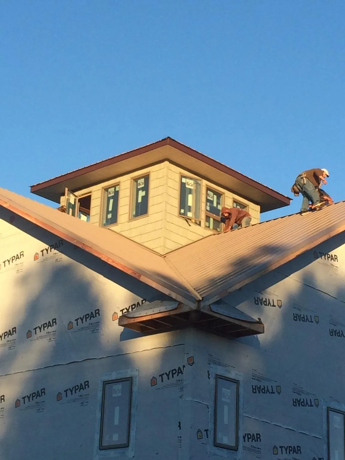 Roofers working around a rooftop cupola on a new metal roof at sunset — Roof Waterproofing in Santa by Roofing Brothers